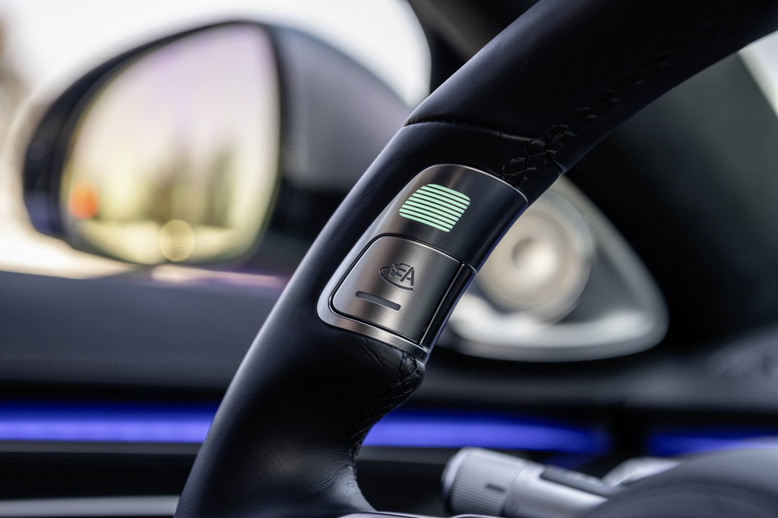 A Mercedes-Benz steering wheel with a green light lit up.