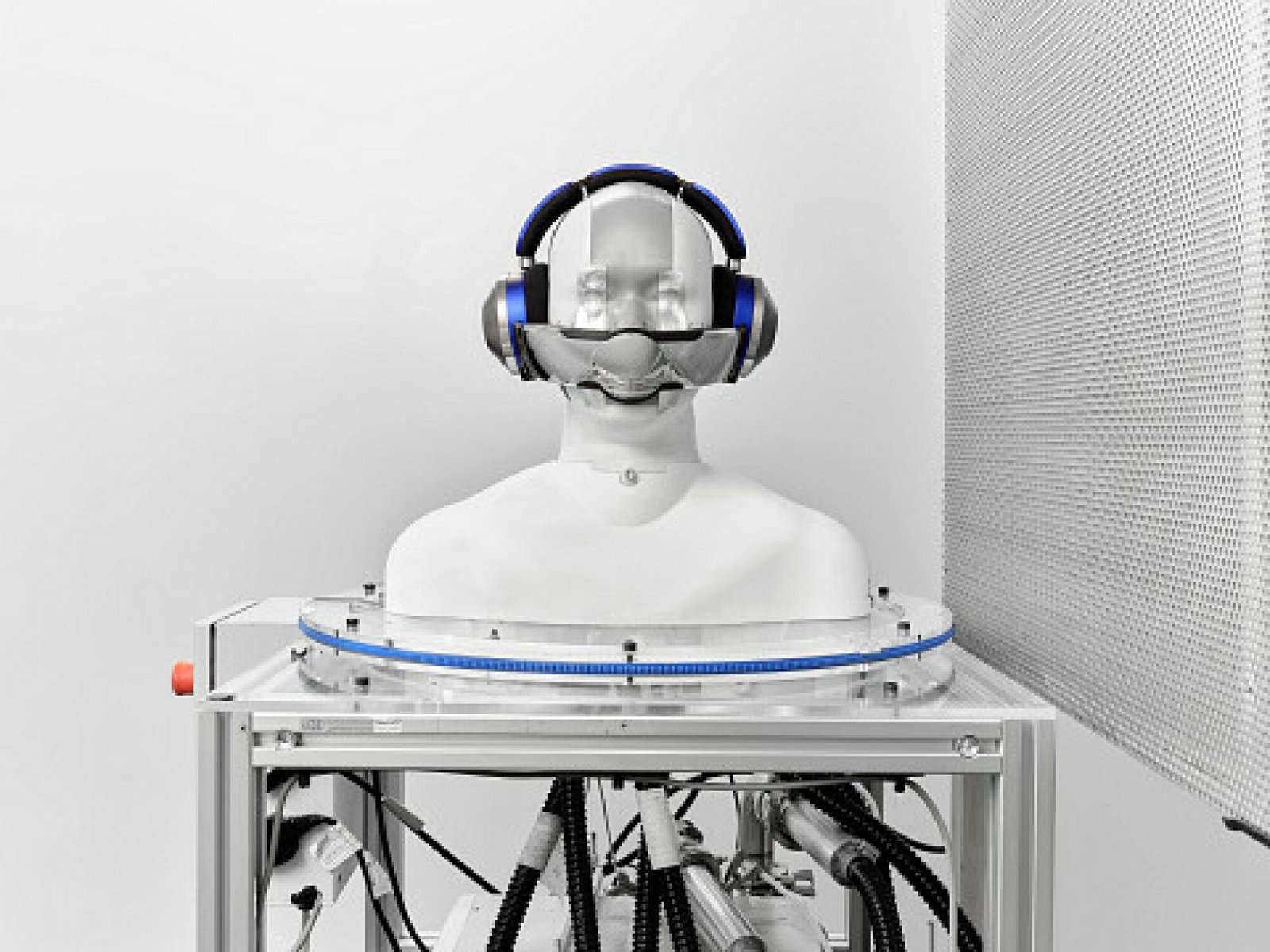 Mannequin wearing over ear headphones with a small visor attached over the nose and mouth area.