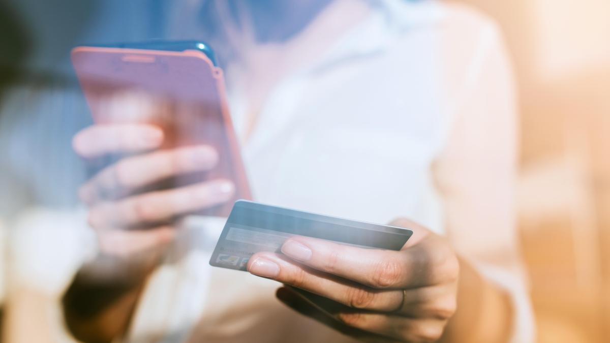 silhouette of woman holding phone and credit card
