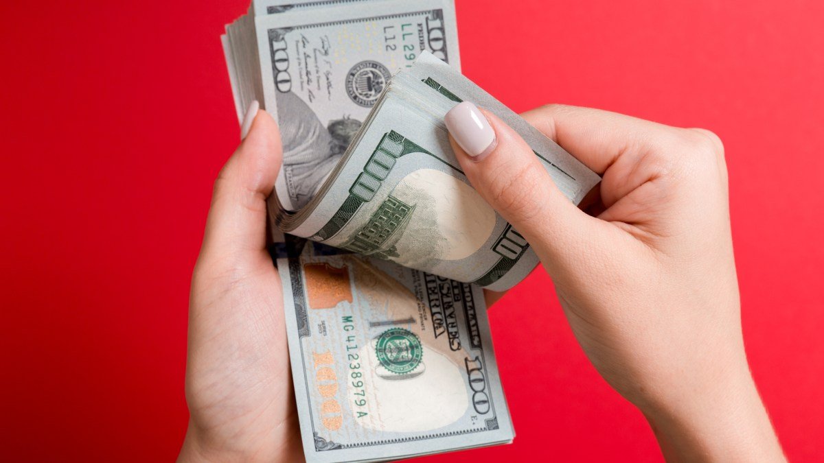 Hands holding a pile of $100 bills