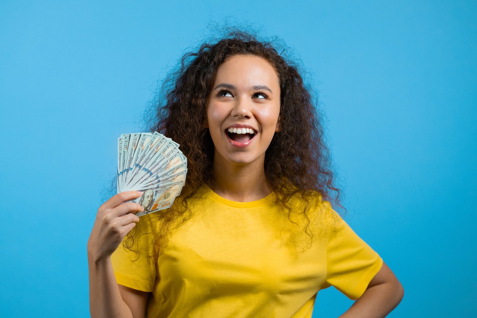 girl in yellow shirt on blue background fanning money