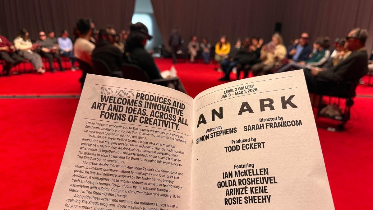 A program for An Ark, a show at The Shed. The inside of the red theater space is visible behind it.