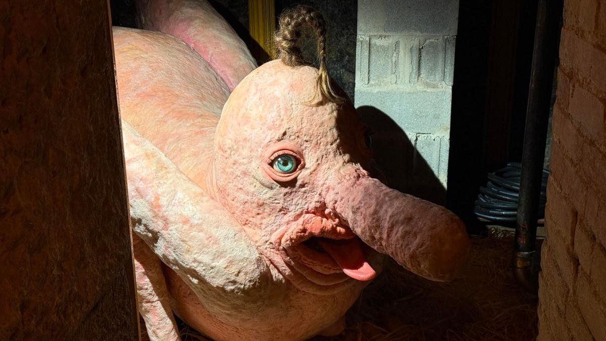 A creepy sculpture of a long-nosed beast with humanlike eyes and hair.